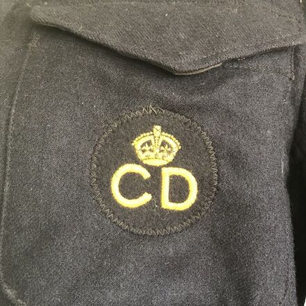 An original CD breast badge sewn to the left pocket of a battledress blouse.